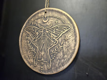 Load image into Gallery viewer, Decorative metal plate with lunar moth design on a dark background