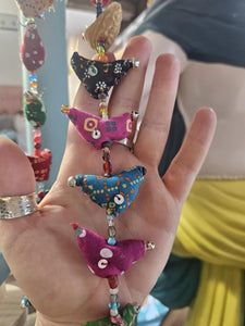 Colourful hanging decorative item with beads and small figures on a grey background www.karmaripon.co.uk